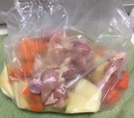 Image of cut-up vegetables and chicken in a storage bag