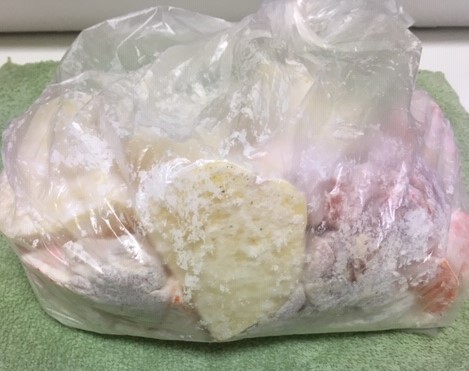 Image of cut-up vegetables and chicken in a storage bag covered with flour