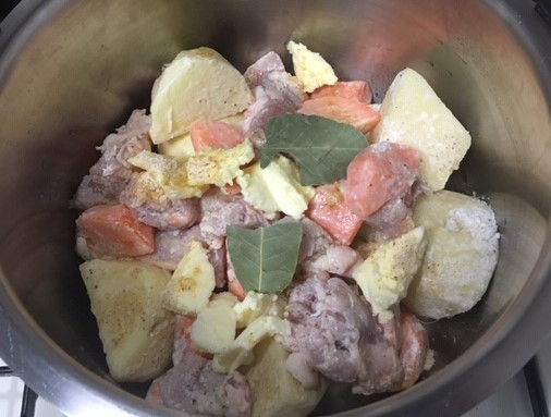Image of onions, chicken, potatoes, and carrots in the inner pot.