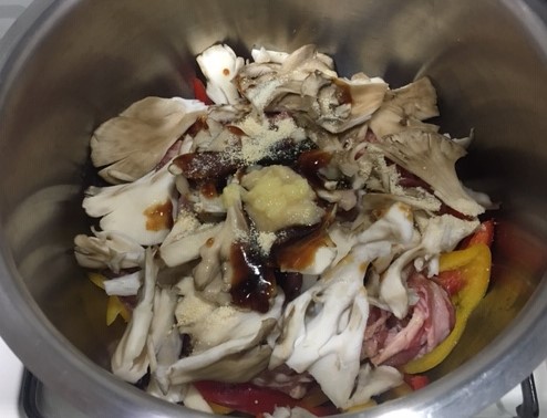 Image of the inner pot with red and yellow peppers, onions, beef, maitake mushrooms, and seasonings.