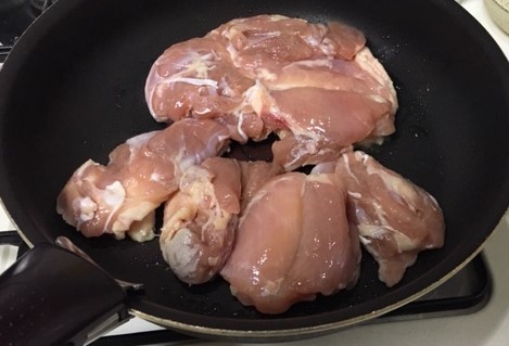 Image Chicken thighs skin side down in a frying pan